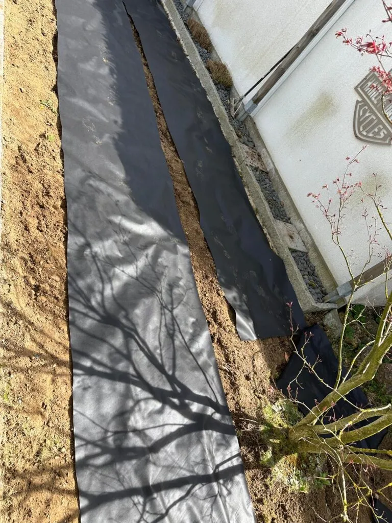 Vorbereitung eines Beetes mit Unkrautvlies entlang der Hauswand in Fürstenfeldbruck